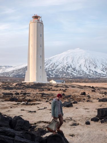 man-walking-near-lighthouse-and-snowy-mountain-4344695